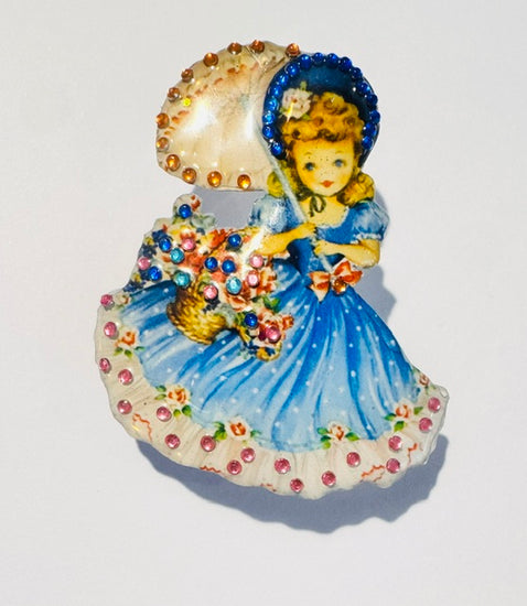 Decorative brooch with a girl in a blue dress holding an umbrella made from recycled  tin cans