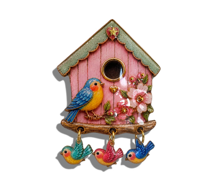 A decorative pink birdhouse brooch with , and three dangling small birds in colorful enamel finish