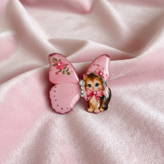 Butterfly-shaped brooch with a cat design in pink