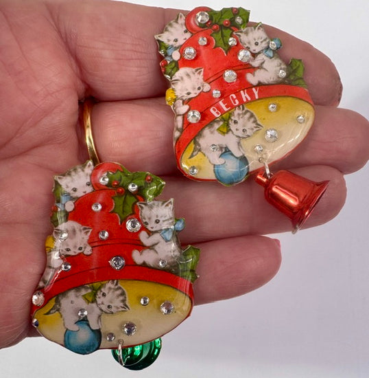Decorative Christmas brooch  with kittens and a bell held in a hand.