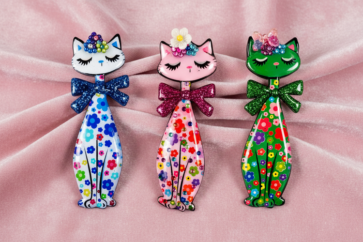 Three Retro tall colorful cat-shaped brooches with floral patterns on a pink background